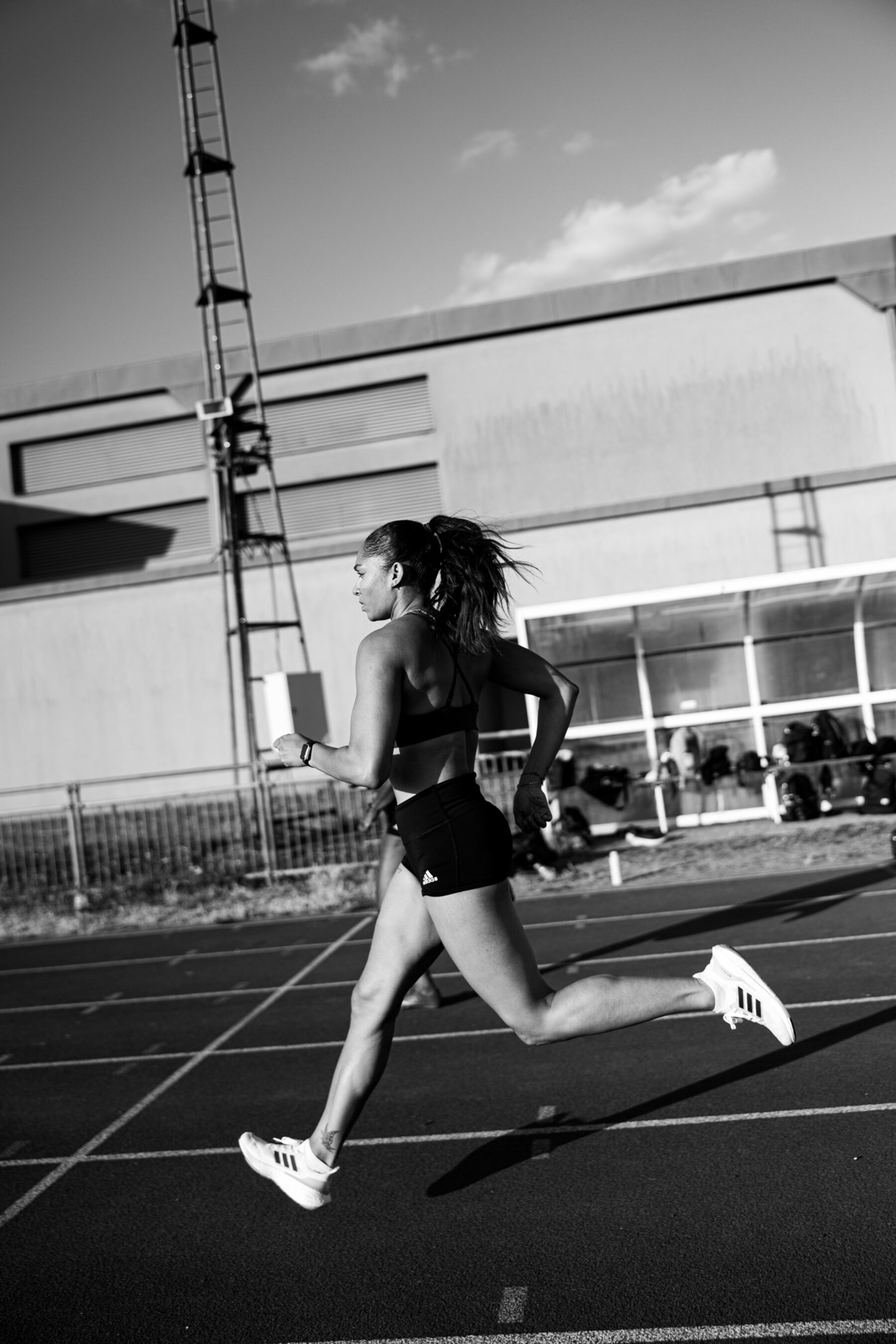 Runner sprinting along an athletics track, mid-stride, shot in black and white